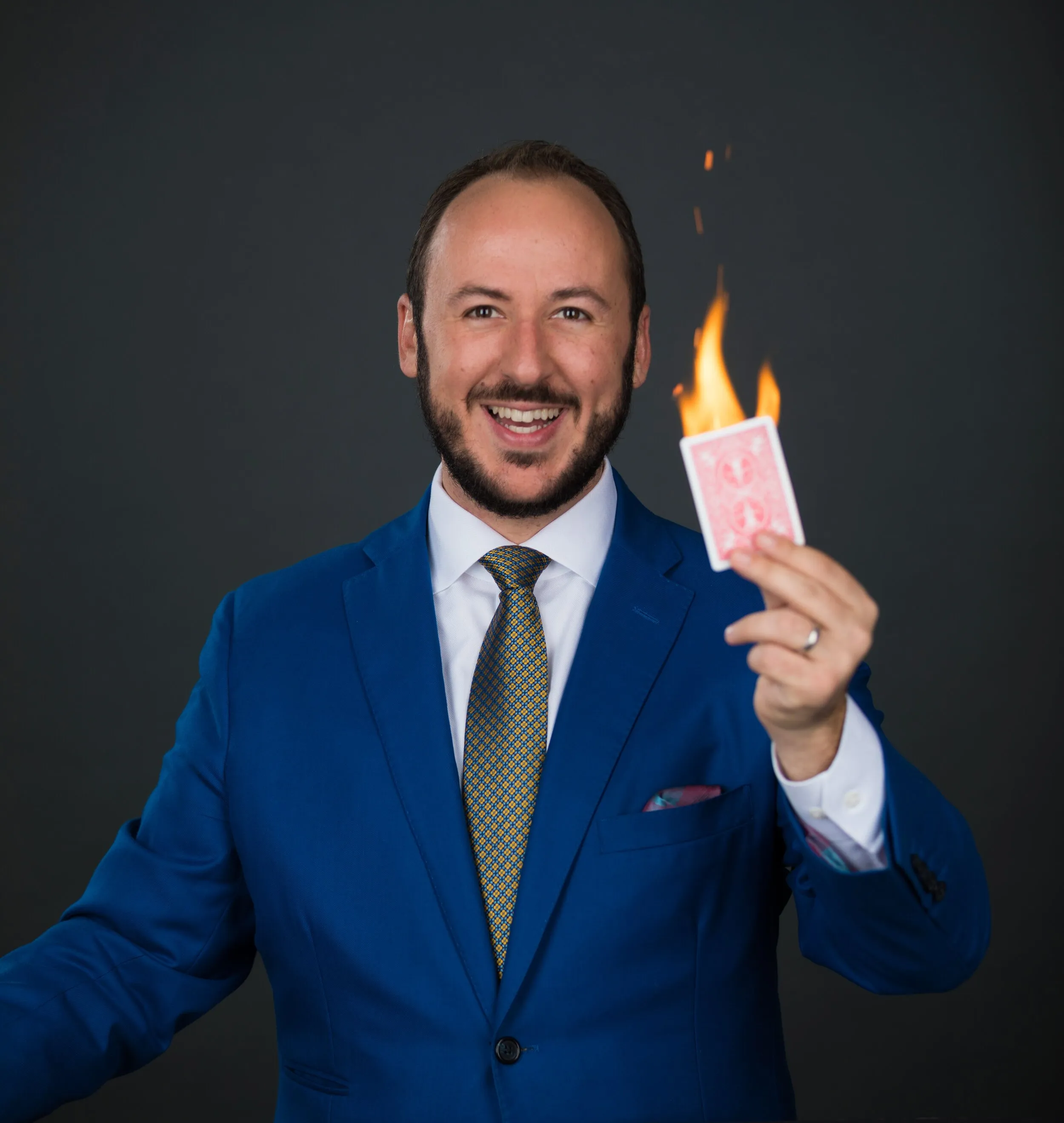 Kostya Kimlat in a blue suit holding a burning playing card