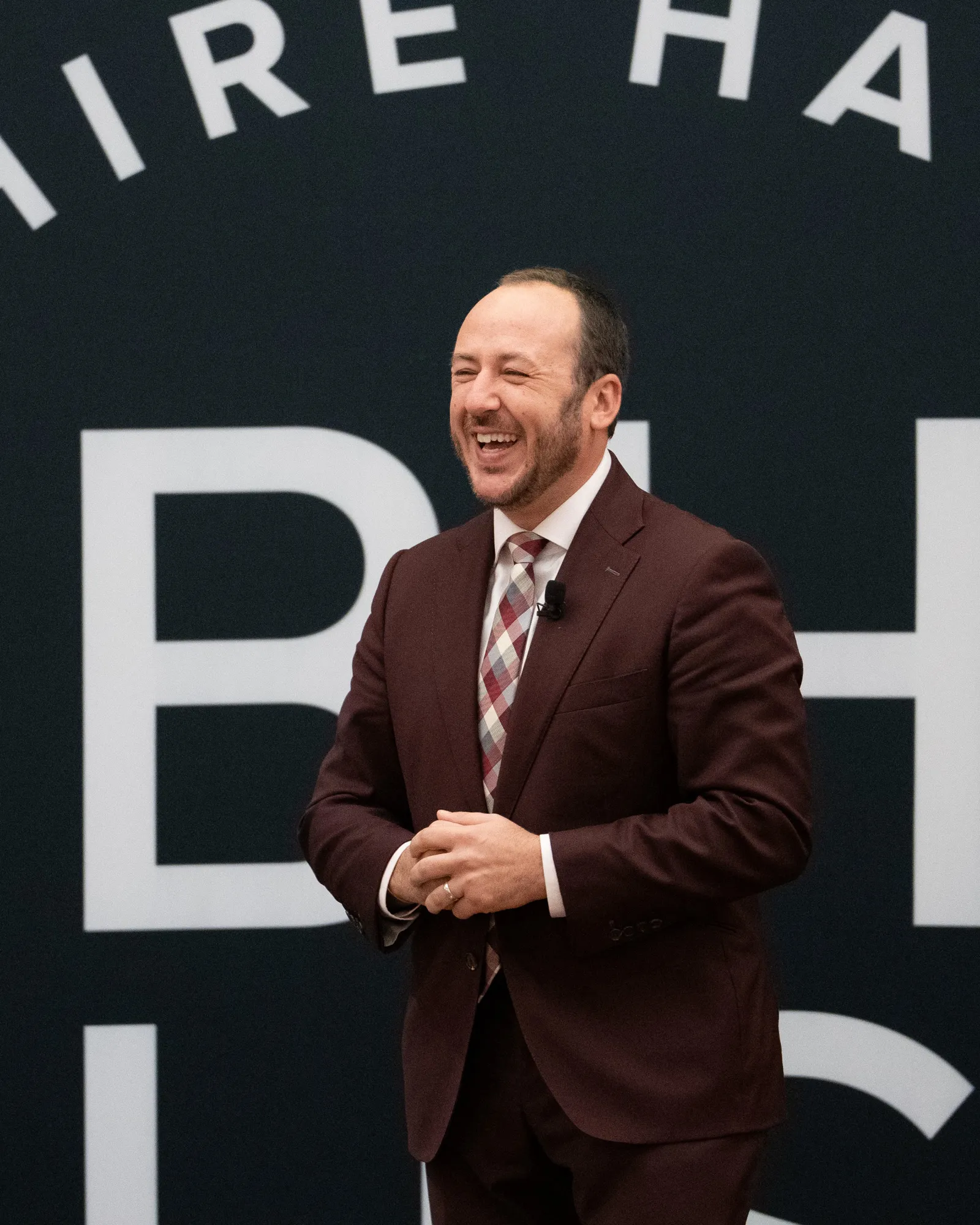 Kostya Kimlat laughing on stage in front of a Berkshire Hathaway HomeServices backdrop