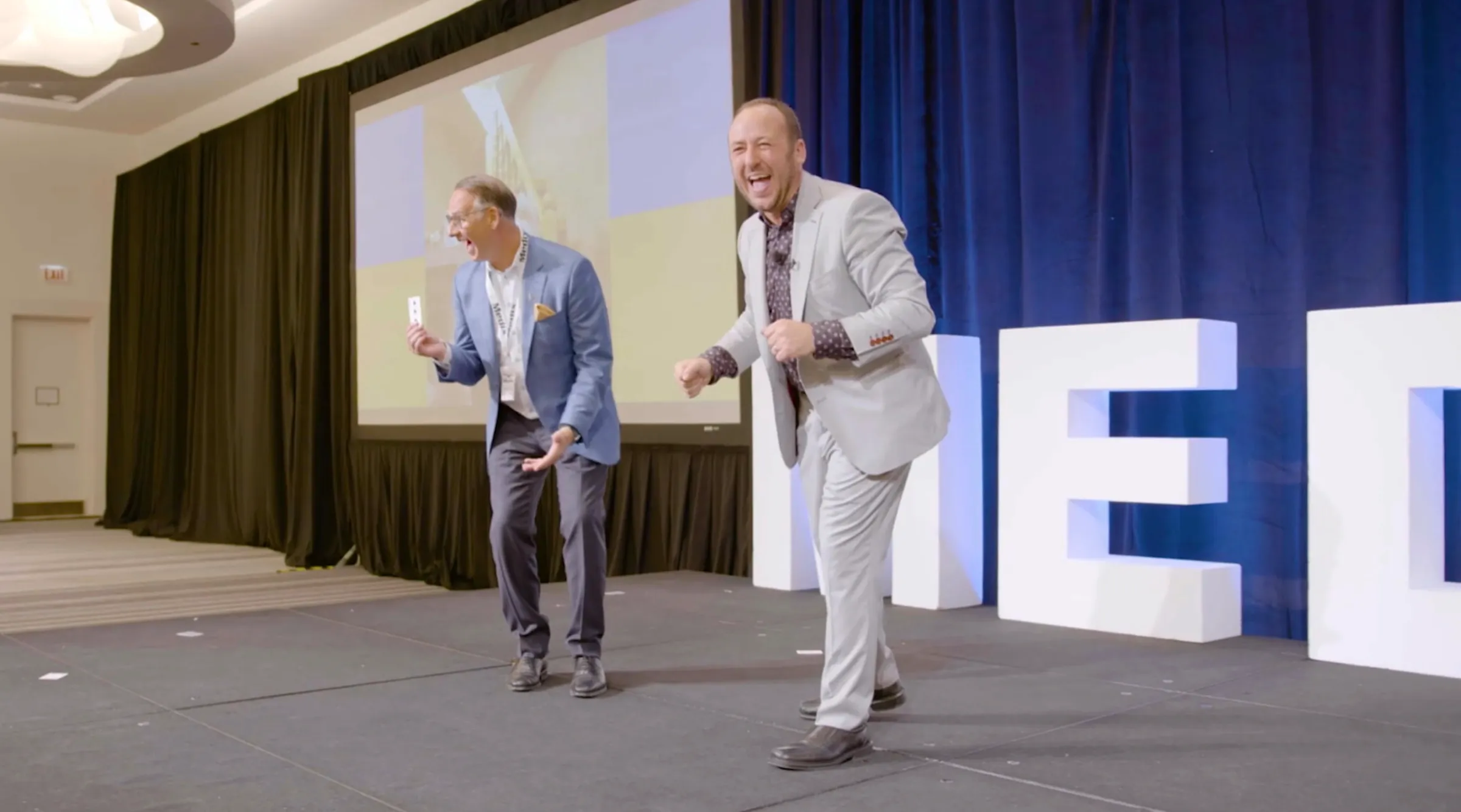 Kostya and a volunteer laughing in disbelief on stage after a card trick