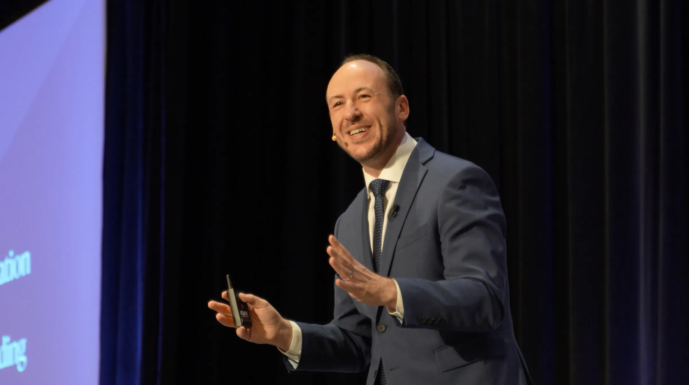 Kostya delivering a keynote, smiling and gesturing toward the audience